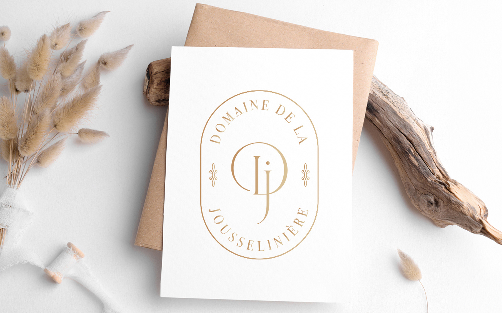 Carte blanche présentant le monogramme DJ du Domaine de la Jousselinière, posée sur du papier kraft
