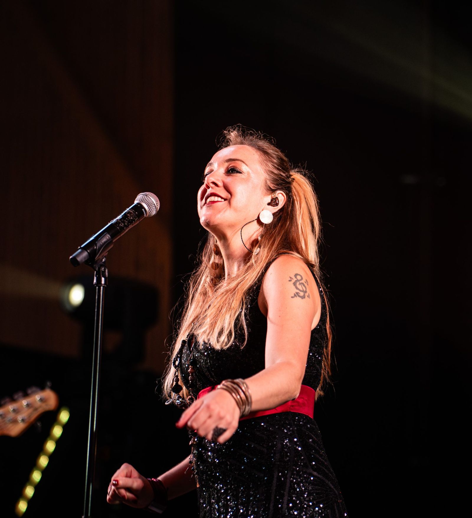 Chanteuse au micro en pleine interprétation sur scène, lumière chaude et fond sombre
