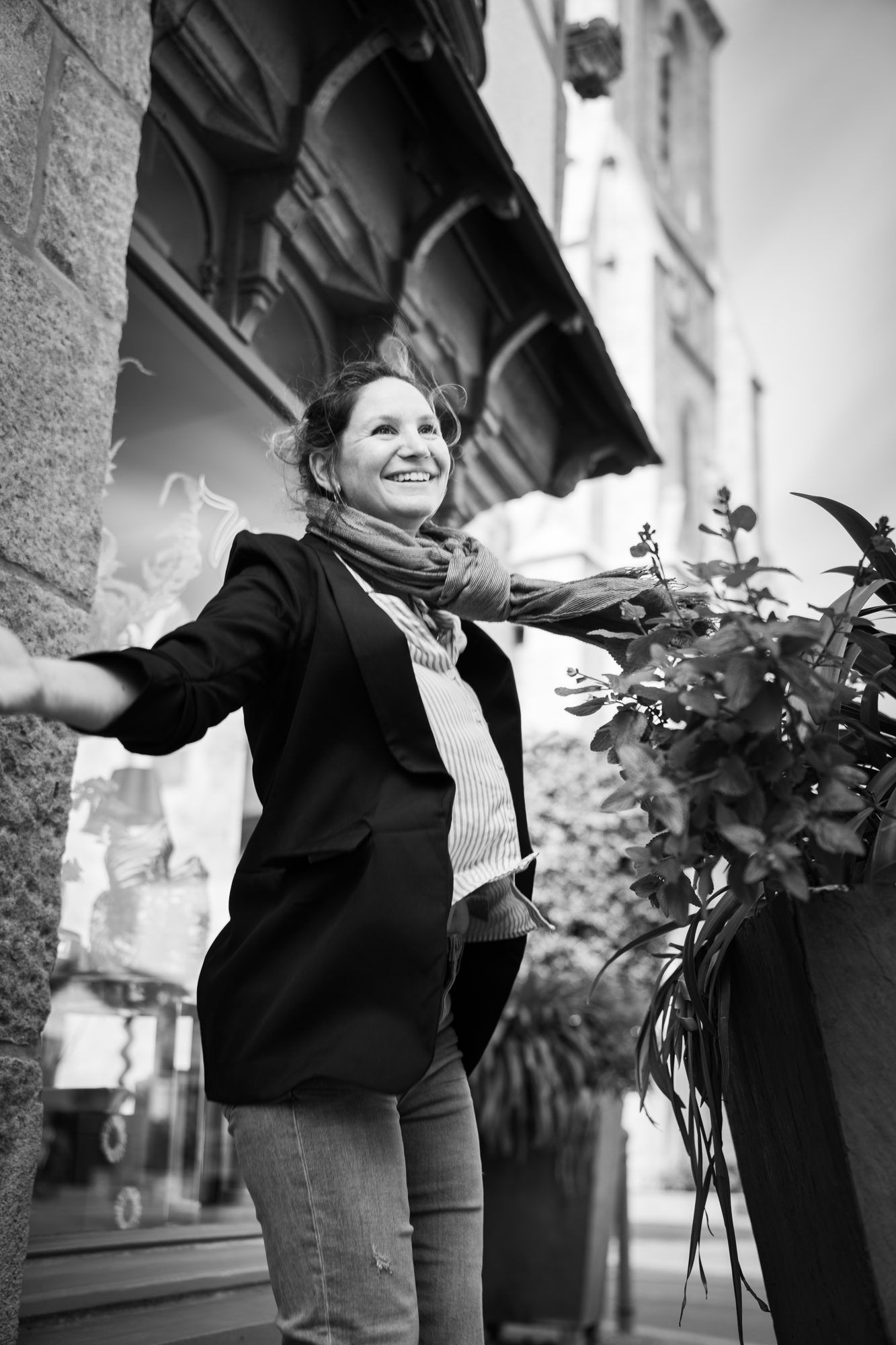 Portrait en noir et blanc d'une fleuriste bras ouverts devant sa boutique
