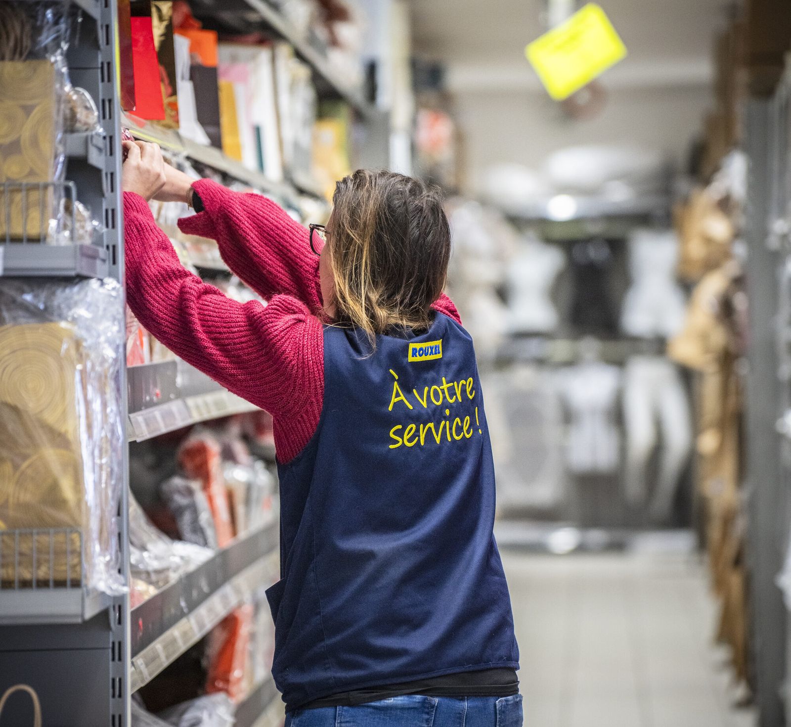Employée d'un magasin en train de réapprovisionner un rayon, reportage d'activité en magasin
